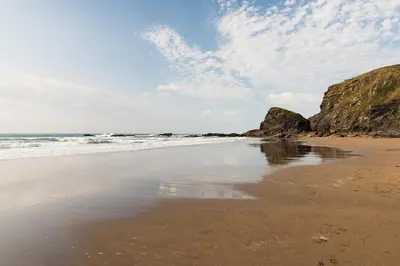 a beach with rocks in the water and a cloudy sky at Trevigue Cottage in Bude