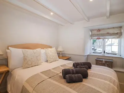 a bedroom with a large bed with two ottomans at Harbour View in Looe