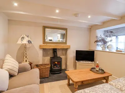 a living room with a fireplace and a table at Harbour View in Looe