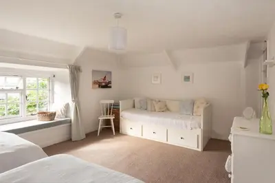 a white bedroom with two beds and a window at Honeysuckle Cottage in Saint Minver
