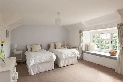 a white bedroom with two beds and a window at Honeysuckle Cottage in Saint Minver