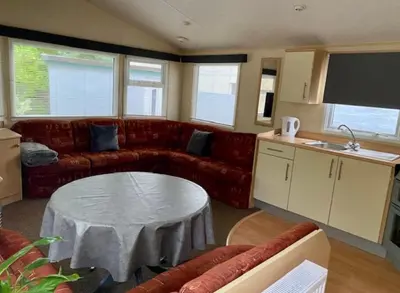 a living room with a couch and a table at Cabin by Beach & Nature Reserve Mon & Fri Check in Days Swanpool Falmouth Cornwall in Falmouth