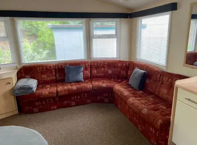 a living room with a brown couch with blue pillows at Cabin by Beach & Nature Reserve Mon & Fri Check in Days Swanpool Falmouth Cornwall in Falmouth