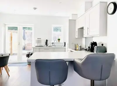 a kitchen with white cabinets and blue chairs at Hayle - 2 bedrooms house with EV parking, 4 beds in Hayle