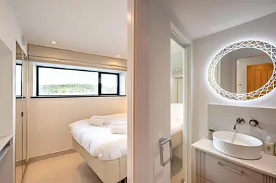 a bathroom with a bed and a sink and a mirror at 2 Bed in Polruan oc-w31943 in Fowey