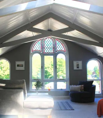 a living room with three windows and a couch at St Monica's in Fowey