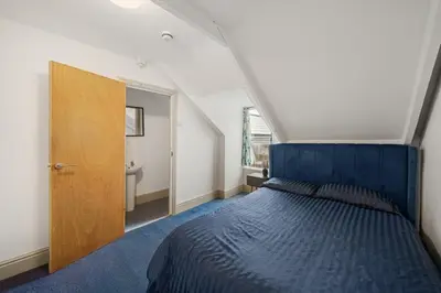 a bedroom with a blue bed and a bathroom at Breakwater Hostel in Newquay