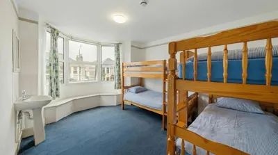 a bedroom with two bunk beds and a sink at Breakwater Hostel in Newquay