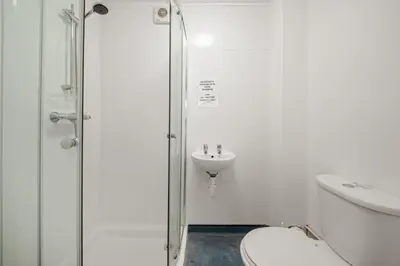a bathroom with a shower and a toilet and a sink at Breakwater Hostel in Newquay