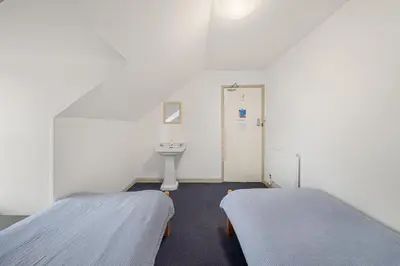 two beds in a white room with a sink at Breakwater Hostel in Newquay