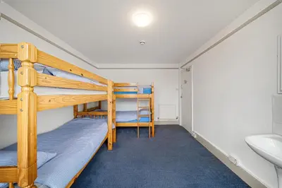 a bunk bed room with two bunk beds and a sink at Breakwater Hostel in Newquay