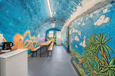 a room with a blue wall with a painting on it at Breakwater Hostel in Newquay