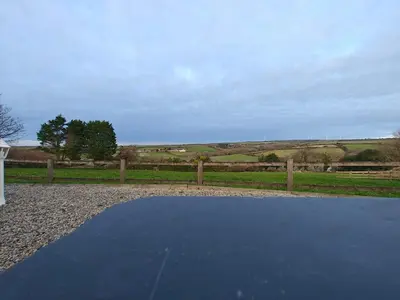 a tennis court in a yard with a fence at Luxury Countryside Shepherds Hut with Hot Tub in Saint Mawgan