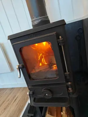 a wood stove with a fire in it at Luxury Countryside Shepherds Hut with Hot Tub in Saint Mawgan