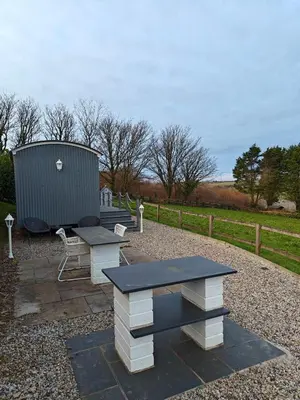 a picnic table and a bench in a park at Luxury Countryside Shepherds Hut with Hot Tub in Saint Mawgan