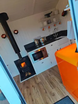 a kitchen with a stove in a tiny house at Luxury Countryside Shepherds Hut with Hot Tub in Saint Mawgan