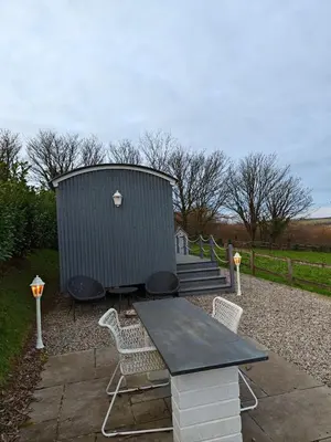 a picnic table and chairs in front of a shed at Luxury Countryside Shepherds Hut with Hot Tub in Saint Mawgan