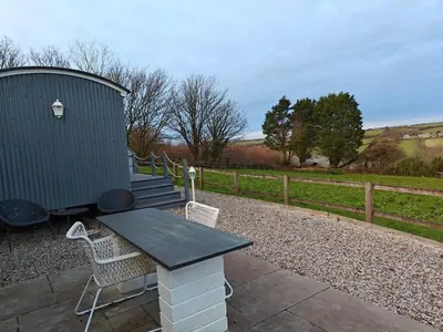 a table and chairs on a patio with a silo at Luxury Countryside Shepherds Hut with Hot Tub in Saint Mawgan