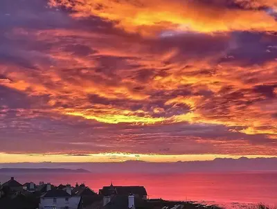 a sunset over the ocean with houses and buildings at Ocean View at Kenwyn in Torpoint