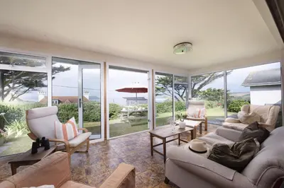 a living room filled with furniture and a bunch of windows at Little Rabbit Hill in Polzeath