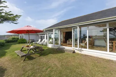 a patio with a table and an umbrella on a house at Little Rabbit Hill in Polzeath