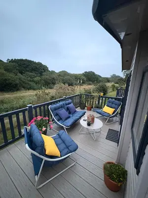 a deck with couches and chairs and a table at Serenity in Saint Erth
