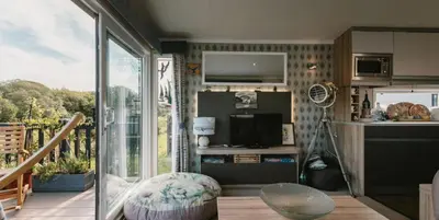 a living room with a kitchen and a balcony at Serenity in Saint Erth