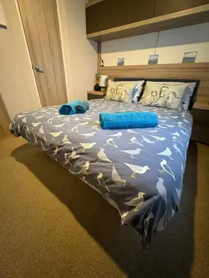 a bedroom with a bed with blue sheets and pillows at Serenity in Saint Erth