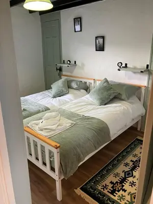 two twin beds in a room with a rug at Knockers Retreat, St Agnes in St. Agnes