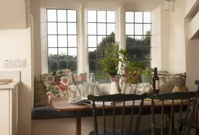 a dining room table with a couch and windows at Besloe in Delabole