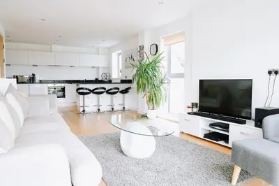 a white living room with a white couch and a tv at Azure 7 Apartment in Newquay