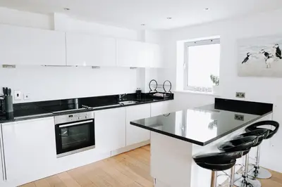 a kitchen with white cabinets and black counter tops at Azure 7 Apartment in Newquay