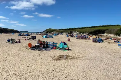 a group of people sitting on a beach at Apartment Close To Porth Beach in Saint Columb Minor