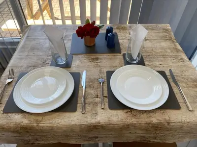a wooden table with white plates and silverware on it at Apartment Close To Porth Beach in Saint Columb Minor