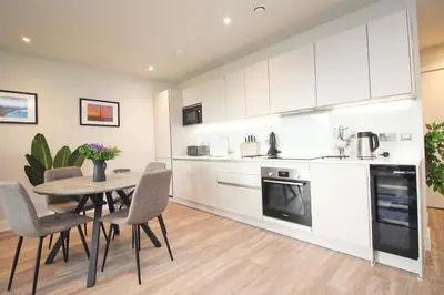 a kitchen with white cabinets and a table and chairs at Secluded two bedroom apartment in Padstow