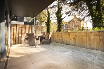 a patio with a table and chairs and a fence at Secluded two bedroom apartment in Padstow