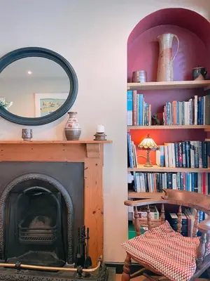 a room with a fireplace and a mirror and bookshelves at Old Bookshop - Unique house in central St Ives with outdoor space in St Ives