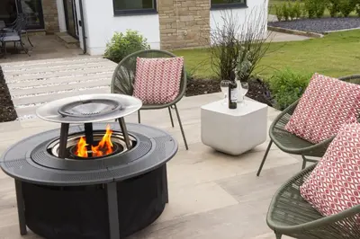 a fire pit in a patio with chairs and a table at Highfield Barton in Camborne