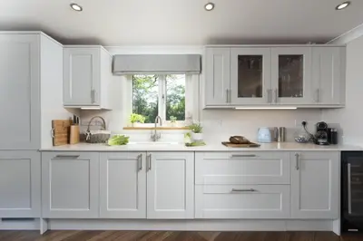 a white kitchen with white cabinets and a window at Highfield Barton in Camborne