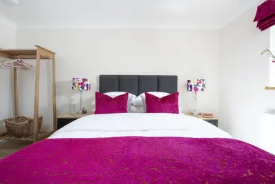 a bedroom with a large bed with purple sheets and pillows at Highfield Barton in Camborne