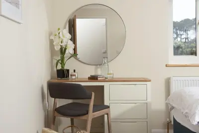 a bedroom with a desk with a mirror and a chair at Highfield Barton in Camborne