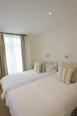 two beds in a hotel room with a window at Cliff House in Padstow