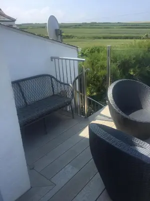 a porch with a bench and two chairs and a table at Cliff House in Padstow