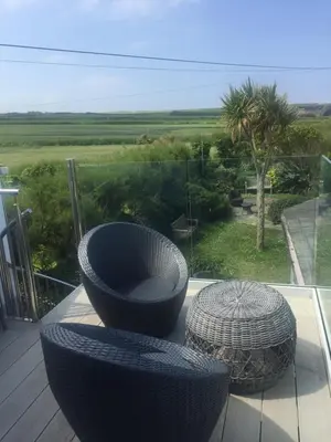 a balcony with two chairs and a view of a field at Cliff House in Padstow