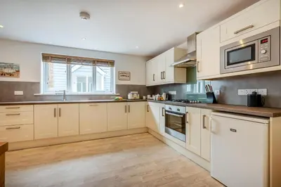 a large kitchen with white cabinets and a window at 2 Bed in St. Issey oc-o27778 in Saint Issey