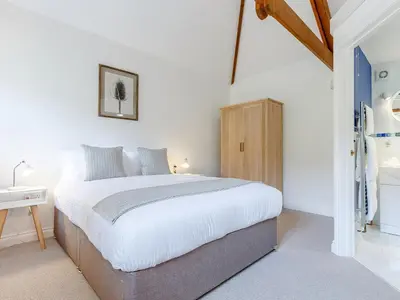 a bedroom with a large bed and a wooden cabinet at Rose's Stable in Truro