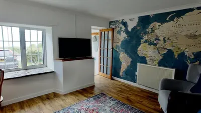 a living room with a tv and a map on the wall at Menadue Cottage, Trenale Lane, Tintagel, Cornwall in Treknow