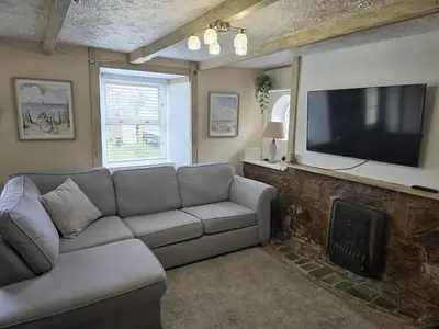 a living room with a couch and a flat screen tv at Cosy Cottage Close to the Beach with Hot Tub in Carnbrea Station