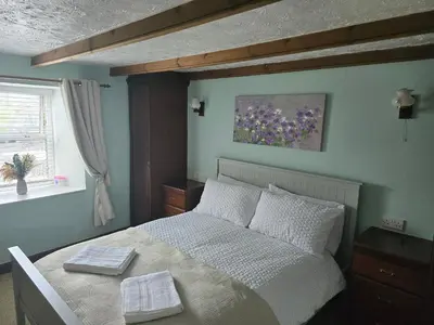 a bedroom with a bed and a painting on the wall at Cosy Cottage Close to the Beach with Hot Tub in Carnbrea Station