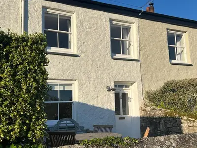 a white house with a table and chairs in front of it at Stunning seaside cottage Charlestown harbour in Charlestown